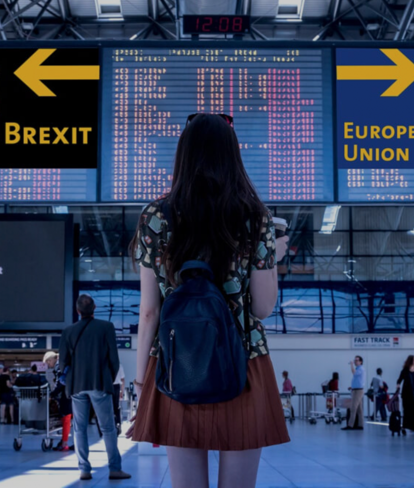 Photo of woman at airport looking at signs that say Brexit and European Union
