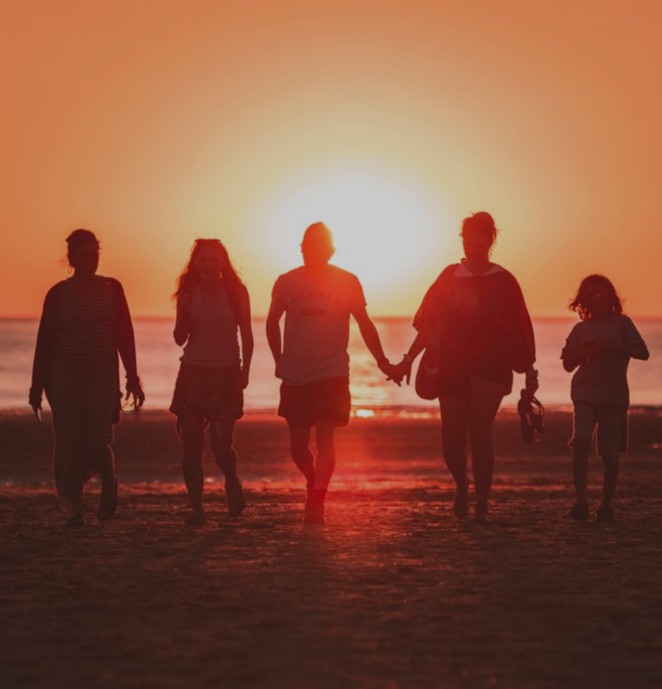Photo of friends on a beach with the sunset.